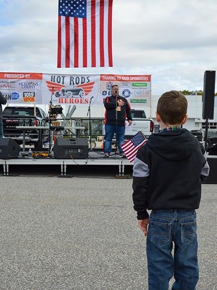 man on stage with child holding flag Bill Dodge Auto Group in Westbrook ME