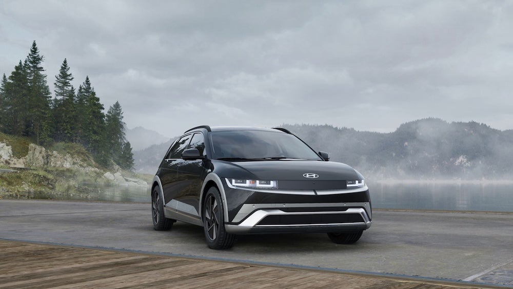 A black 2026 Hyundai Ioniq 5 SUV parked at the edge of a misty mountain lake