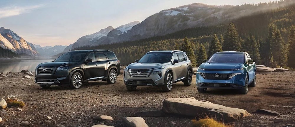 Three Nissan SUVs parked beside a mountain lake